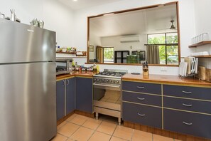 A kitchen with a stainless steel refrigerator, a stove, and a large mirror above the counter.