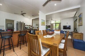 A modern kitchen with a dining area, bar stools, and a TV.
