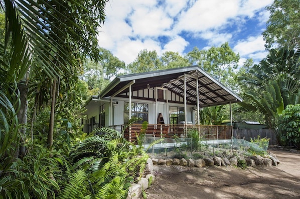 Ein Haus mit überdachter Veranda, umgeben von üppiger tropischer Vegetation.