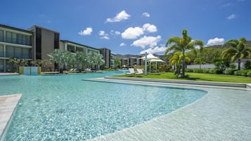 A swimming pool with lounge chairs, a gazebo, and modern buildings in the background.