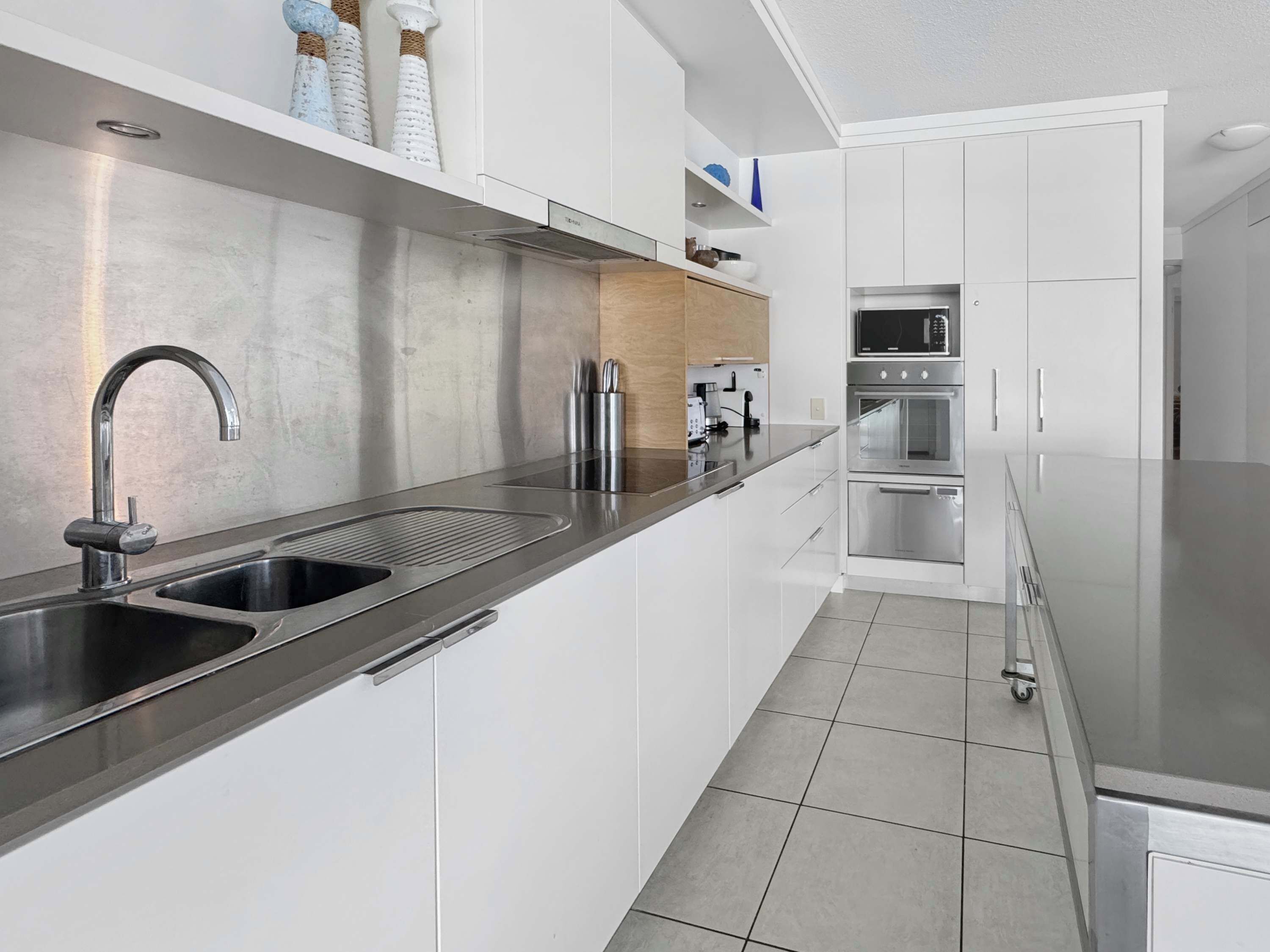 A modern kitchen with stainless steel appliances, a double sink, and white cabinetry.