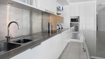 A modern kitchen with stainless steel appliances, a double sink, and white cabinetry.