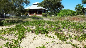 A beachfront property with a large house, sandy beach, and lush vegetation.