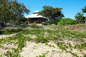 Una propiedad frente a la playa con una casa grande, una playa arenosa y abundante vegetación.