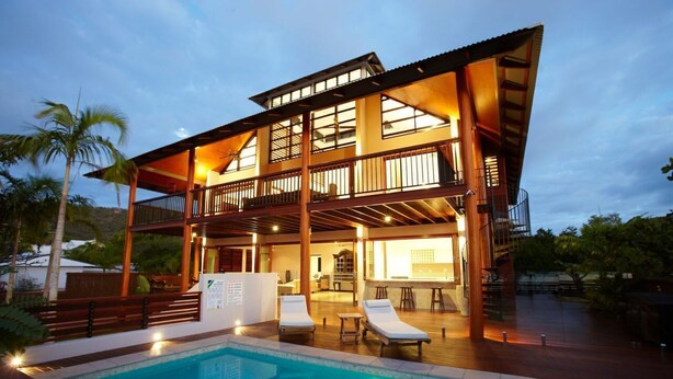 A two-story building with a pool, lounge chairs, and a covered patio area.