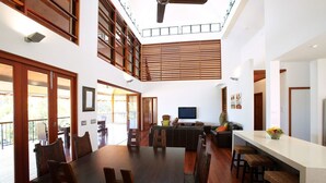 A spacious dining area with a high ceiling, wooden flooring, and a large dining table surrounded by chairs.