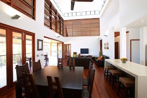 A spacious dining area with a high ceiling, wooden flooring, and a large dining table surrounded by chairs. - Villa Kembali (Horseshoe Bay)