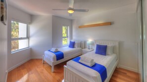 A bedroom with two beds, a ceiling fan, and a window.