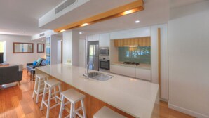 Una cocina moderna con una isla grande, taburetes de bar y electrodomésticos integrados.