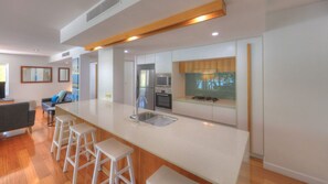 A modern kitchen with a large island, bar stools, and built-in appliances.