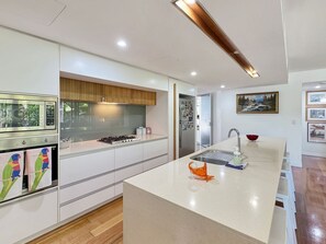 A modern kitchen with white cabinetry, a central island, stainless steel appliances, and a view of the outdoors.