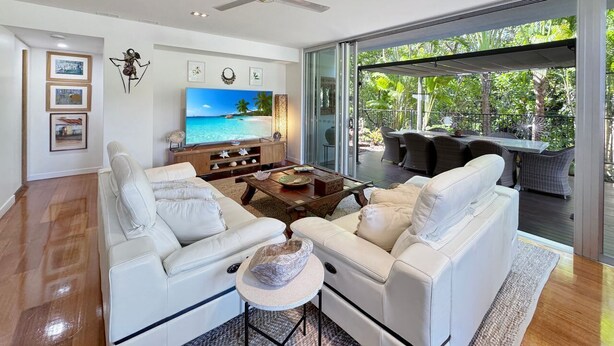 A modern living room with a white sofa set, a coffee table, and a TV. - Maggies Beachfront Apt. 2 (Horseshoe Bay)
