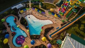 Vue aérienne d’un complexe hôtelier doté d’une grande piscine, de toboggans aquatiques et d’une plage.