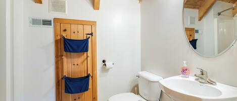 A bathroom with a wooden door, a toilet, a sink, and a mirror.