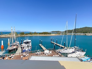 A marina with boats docked, a sandy beach, and a clear blue sky.