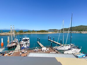 Ein Yachthafen mit vertäuten Booten, ein Sandstrand und ein klarer, blauer Himmel.