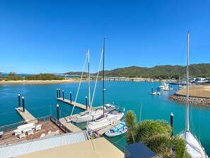 A marina with boats docked, a sandy beach, and a clear blue sky.