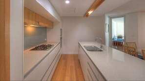 A modern kitchen with a gas stove, a sink, wooden cabinets, and a dining area with a table and chairs.