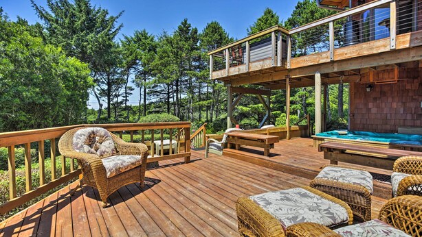 Una terraza de madera con mobiliario de mimbre, una bañera de hidromasaje y una silla de madera.