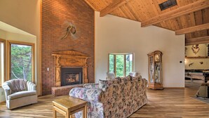 Un salón amplio con chimenea, pisos de madera y ventanas grandes.