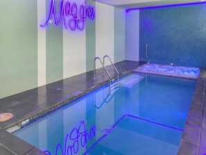 A swimming pool with a neon sign reading 'Moggies' and a tiled wall with a textured pattern. - Maggies Beachfront Apt. 9 (Horseshoe Bay)