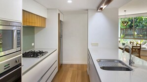 A modern kitchen with white cabinetry, a stainless steel range, a microwave, and a gas stove.