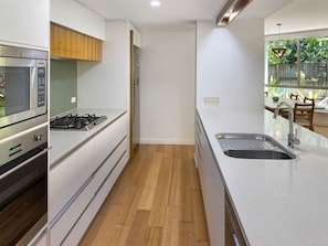 A modern kitchen with white cabinetry, a stainless steel range, a microwave, and a gas stove.