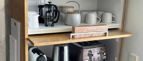 Una cocina con cafetera, hervidor, tostadora y una caja de cápsulas Nespresso.