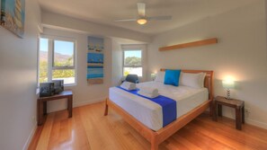 A bedroom with a bed, a ceiling fan, a window, and a wall-mounted artwork. - Maggies Beachfront Apt. 6 (Horseshoe Bay)
