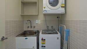 A laundry area with a washing machine, a dryer, and a sink. - Blue on Blue Apartment 921 (Nelly Bay)