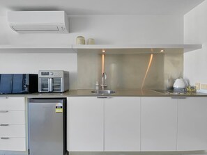Eine moderne Küche mit Einbauofen, Mikrowelle und Kühlschrank, einem Edelstahl-Spülbecken und einer kompakten Arbeitsfläche.