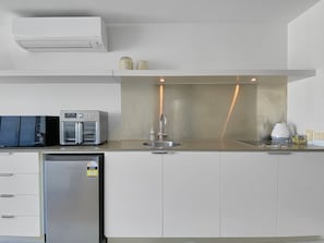 A modern kitchen with a built-in oven, microwave, and refrigerator, a stainless steel sink, and a compact countertop area. - Blue on Blue Superior Studio Room 1241 (Nelly Bay)