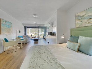 Ein modernes Hotelzimmer mit einem großen Bett, einer Essecke und Blick ins Freie.