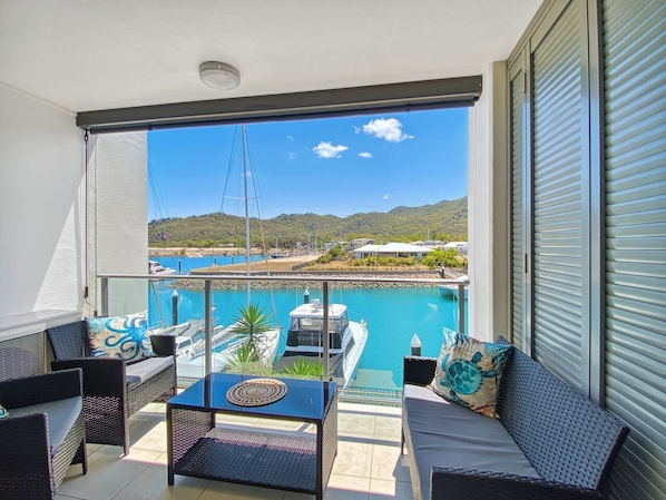 A balcony with a view of a marina, a pool, and hills. - Blue on Blue Studio Room 1222 (Nelly Bay)