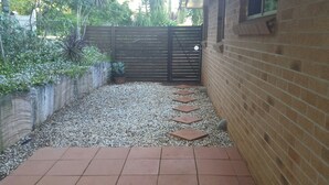 Un camino empedrado que conduce a una zona vallada con un muro de ladrillo y una cerca de madera.