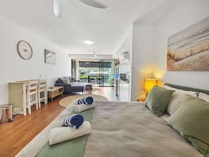Ein Schlafzimmer mit einem großen Bett, einem Schreibtisch, einem Sessel, einer Couch und Blick ins Freie.