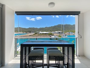 Ein Balkon mit Tisch und Stühlen mit Blick auf ein Schwimmbad und Berge.