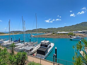Ein Hafen mit vertäuten Booten, einem klaren blauen Himmel und einer hügeligen Landschaft im Hintergrund.