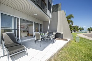 Une terrasse extérieure moderne, aménagée avec une table à manger, des chaises et un fauteuil de relaxation.