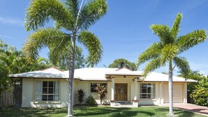 Uma casa de dois andares com varanda da frente, garagem e gramado bem cuidado.