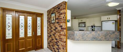 Una cocina con encimera de piedra, microondas y refrigerador.