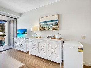A modern room with a white cabinet, a small table with a lamp, and a refrigerator.