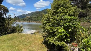 Une vue paisible sur un lac, avec une végétation luxuriante et des collines qui se dessinent à l’horizon.