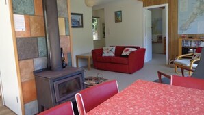Un salon chaleureux avec un canapé rouge, une table en bois et une cheminée.