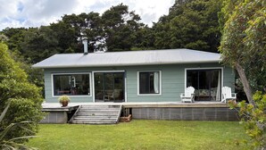 Une maison moderne dotée d’une grande terrasse, de portes-fenêtres coulissantes et d’une pelouse bien entretenue.