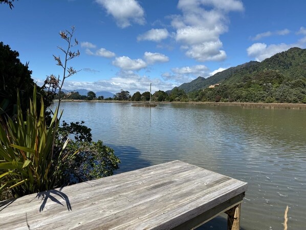 A wooden dock extending into a calm lake, surrounded by lush greenery and hills in the background.