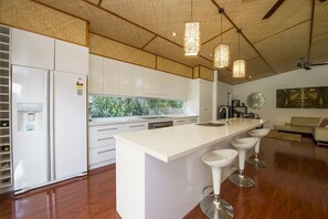 A modern kitchen with a central island, white cabinetry, and pendant lighting. - Serene Place, 22 Serene Place-BOM (Nelly Bay)
