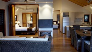 Een moderne hotelkamer met een bed, bank, televisie, kitchenette en eethoek.