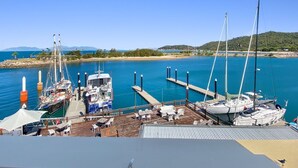 Ein Yachthafen mit vertäuten Booten, eine anlegende Mole und ein klarer Himmel.