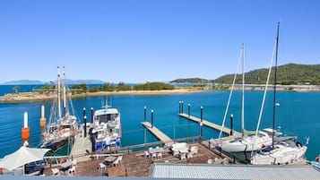 A marina with boats docked, a pier extending into the water, and a clear sky.